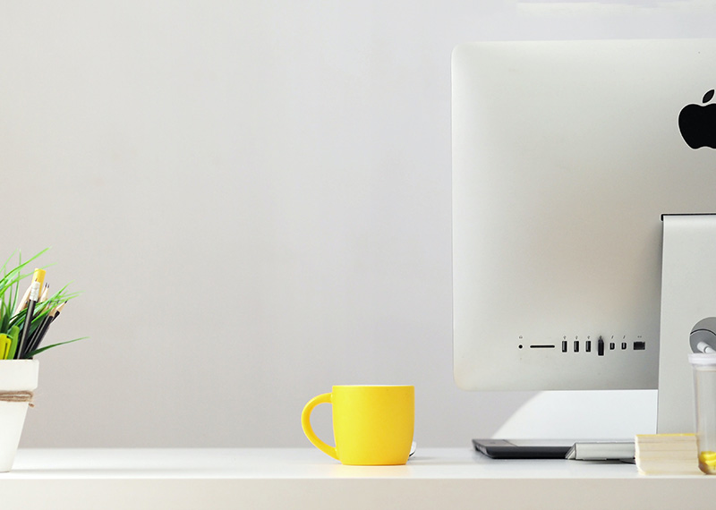 Schreibtissch mit iMac und gelber Kaffeetasse